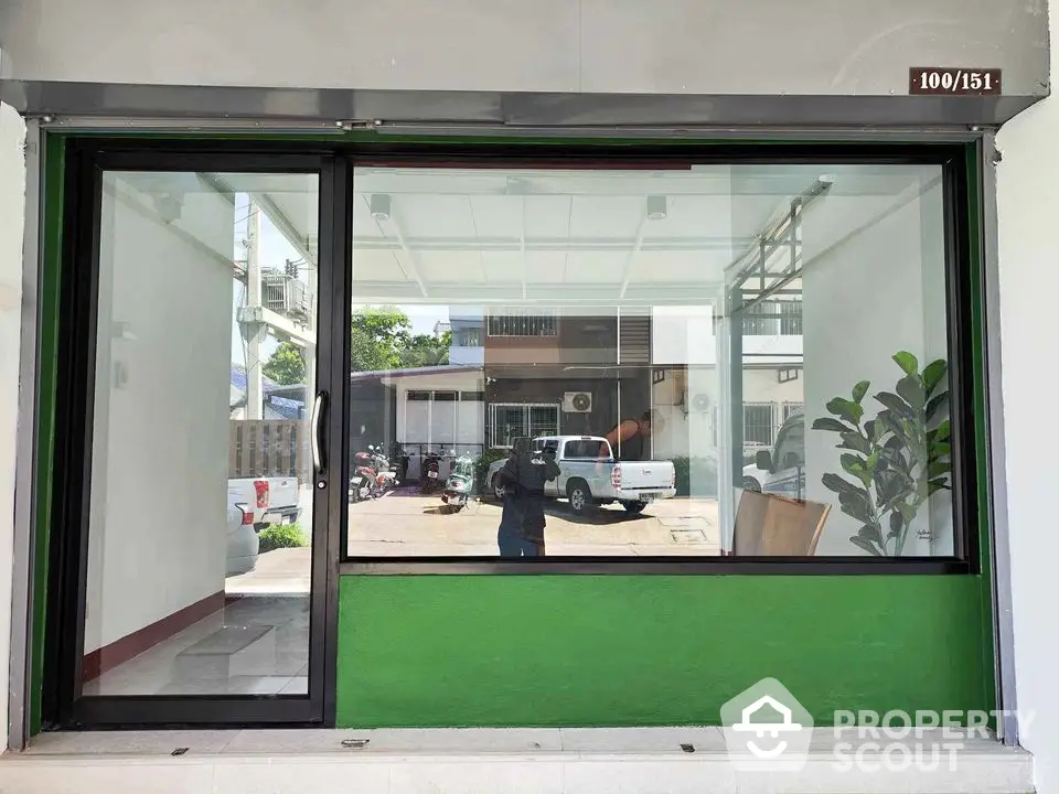 Modern storefront with large glass window and green accent wall