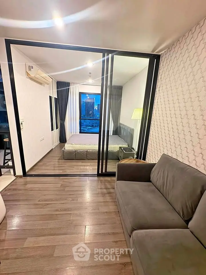 Modern apartment with glass partition, cozy living area, and city view from the bedroom.