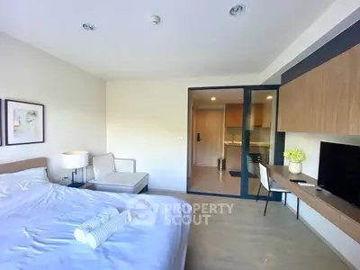 Modern bedroom with stylish decor and workspace, featuring a cozy bed and sleek furniture.