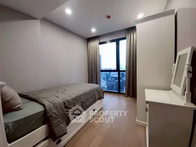 Cozy bedroom with modern decor and large window offering city views.