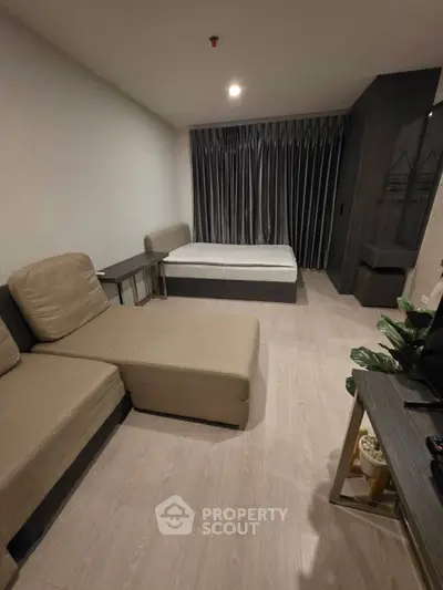 Modern studio apartment with cozy living area and bed, featuring sleek design and neutral tones.