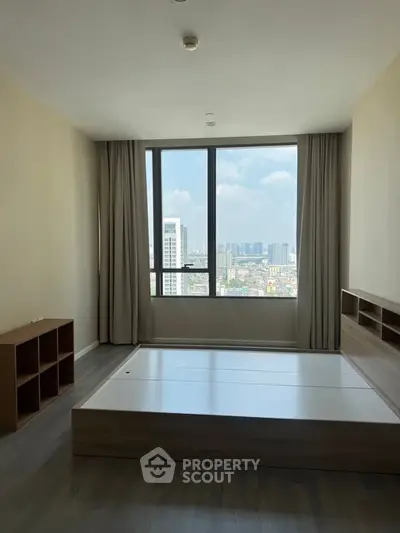 Spacious bedroom with large window offering stunning city views, featuring modern minimalist design and ample natural light.