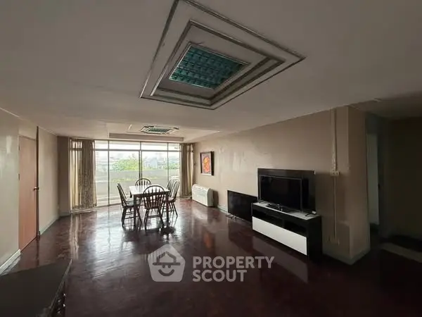 Spacious living room with dining area and large windows for natural light.