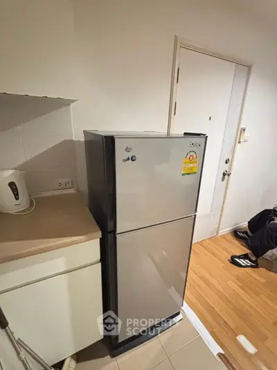 Compact kitchen corner with sleek stainless steel fridge and modern appliances.