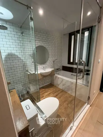 Modern bathroom with glass shower, bathtub, and stylish fixtures.