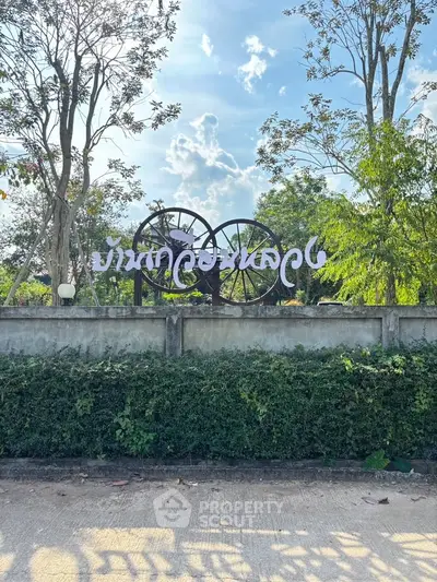 Charming garden entrance with rustic wheel decor and lush greenery under a bright blue sky.