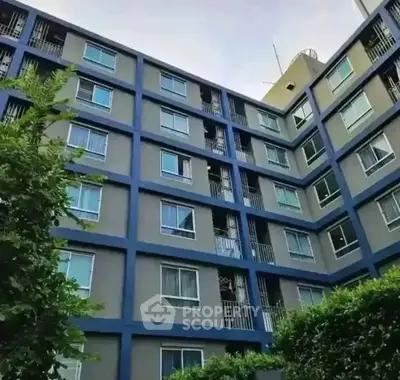Modern apartment building exterior with lush greenery and multiple windows.