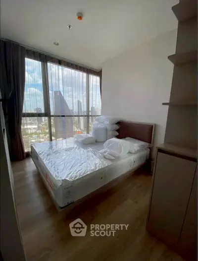 Modern bedroom with large windows offering stunning city views and natural light.