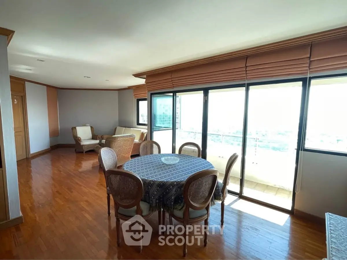 Spacious living room with elegant dining area and large windows offering stunning city views.