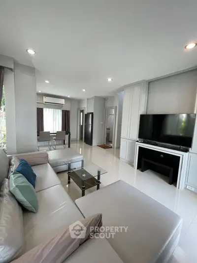 Spacious modern living room with large sofa and flat-screen TV, ideal for relaxation.