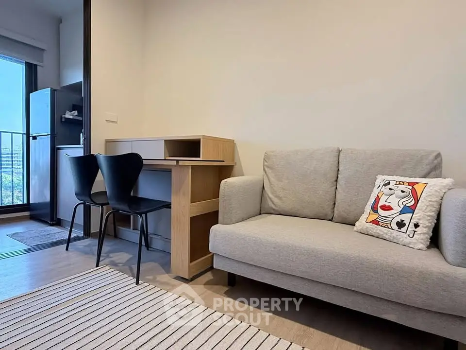 Modern living room with cozy sofa, stylish desk, and balcony view in urban apartment.