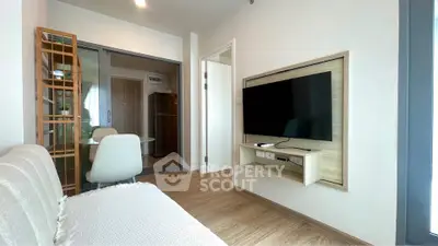 Modern living room with wall-mounted TV and cozy seating area in a stylish apartment.