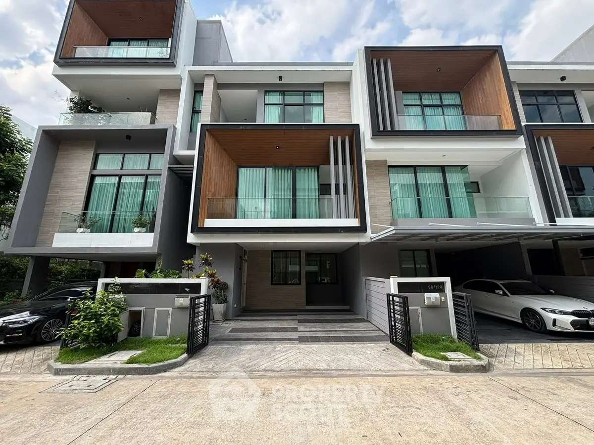 Modern multi-story townhouse with large windows and sleek design, featuring a spacious driveway and contemporary facade.