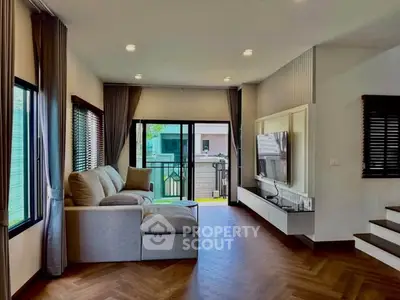 Spacious living room with modern decor and large windows offering natural light and outdoor view.