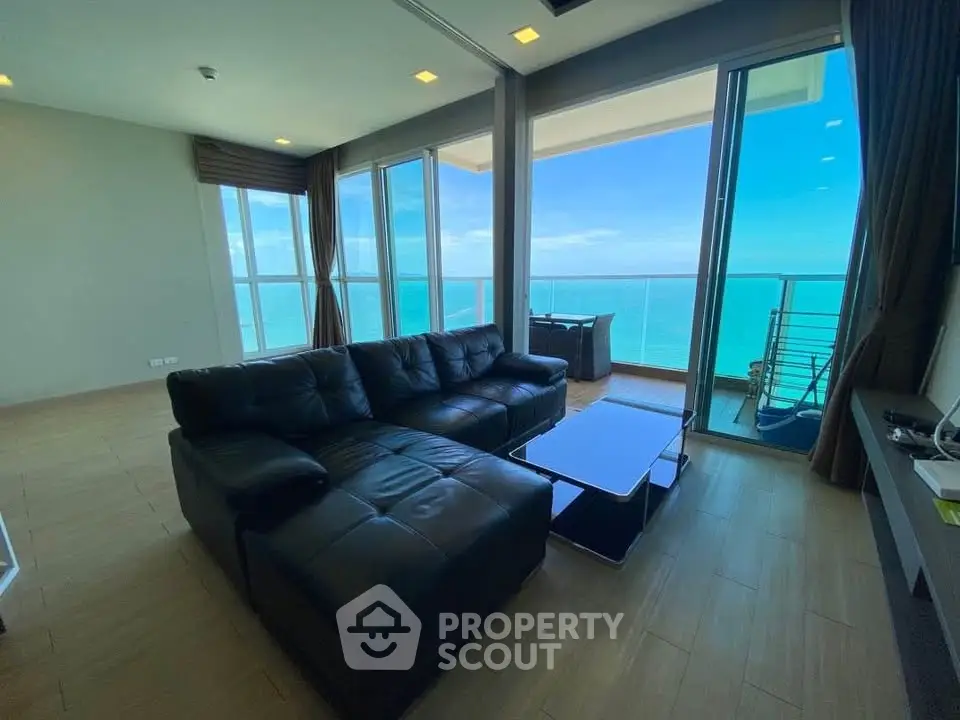 Luxurious living room with stunning ocean view and spacious balcony in modern high-rise apartment.