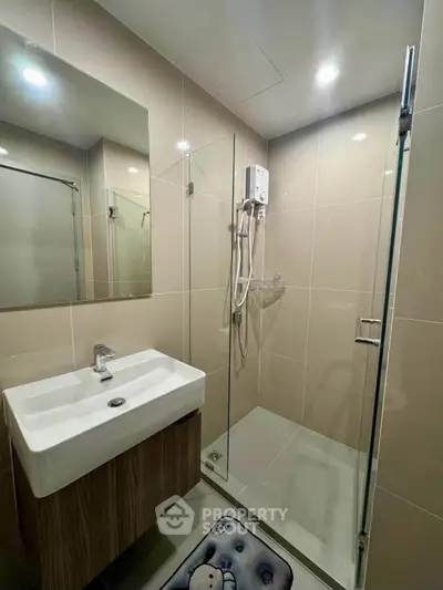 Modern bathroom with glass shower and sleek sink in contemporary apartment.