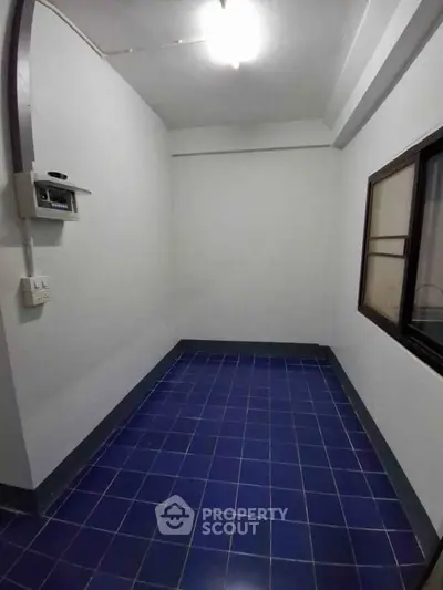 Compact storage room with blue tiled floor and white walls, ideal for organizing.