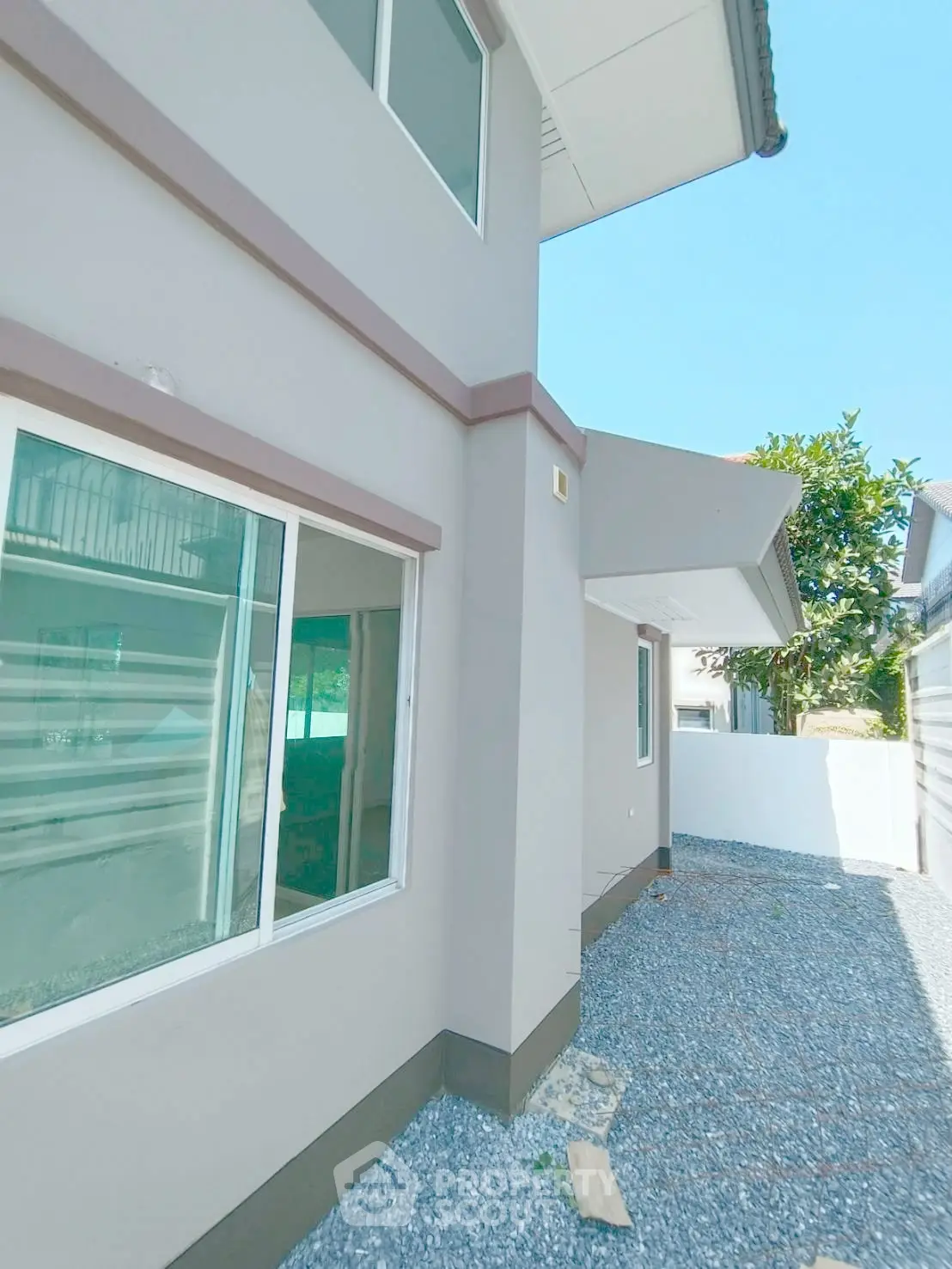 Modern residential building exterior with large windows and gravel pathway