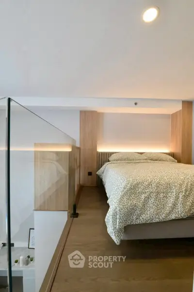 Modern loft bedroom with stylish decor and glass railing, showcasing a cozy and inviting atmosphere.