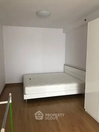 Minimalist bedroom with white bed and wardrobe on wooden flooring