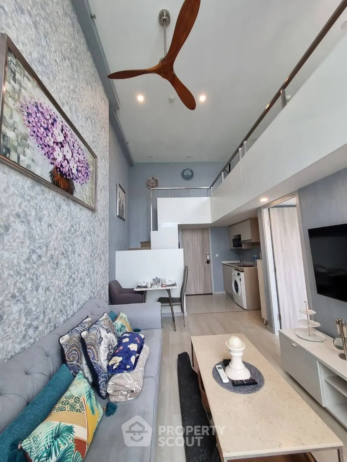 Stylish modern living room with high ceiling and mezzanine, featuring elegant decor and cozy seating.