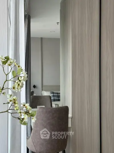 Modern bedroom with stylish decor and elegant furniture, featuring a cozy chair and floral accents.
