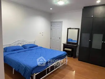 Spacious bedroom with blue bedding and modern wardrobe in a cozy apartment.