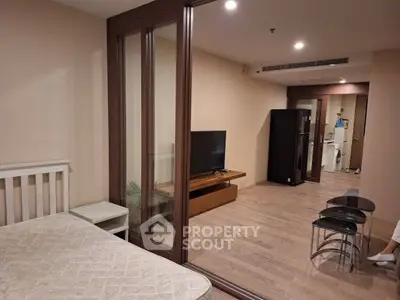 Modern apartment interior with wooden flooring, glass partition, and sleek furniture.