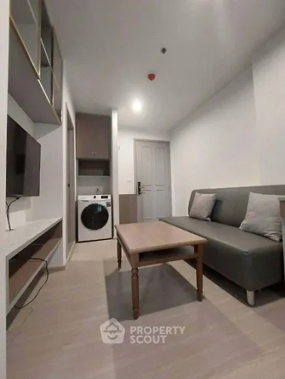 Modern living room with washing machine and sleek furniture in a compact apartment.