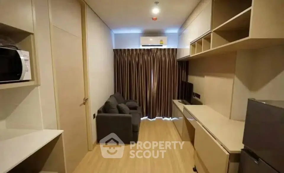 Modern compact living room with sofa, TV, and built-in storage in a cozy apartment.