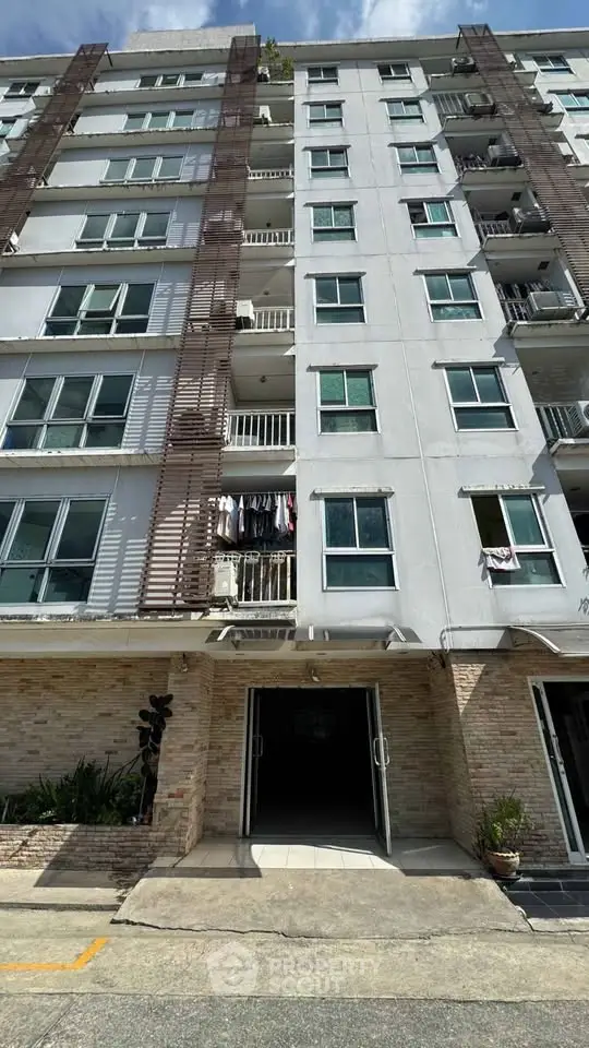 Modern apartment building exterior with balconies and entrance, showcasing urban living.