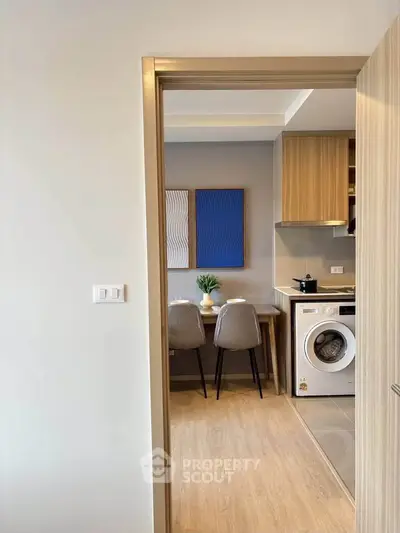 Modern kitchen with dining area and built-in washing machine, featuring stylish decor and wooden cabinetry.