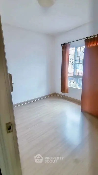Bright empty room with wooden flooring and large window, ideal for customization.
