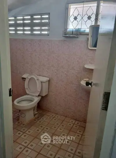 Cozy bathroom with pink tiles and window, ideal for compact spaces.