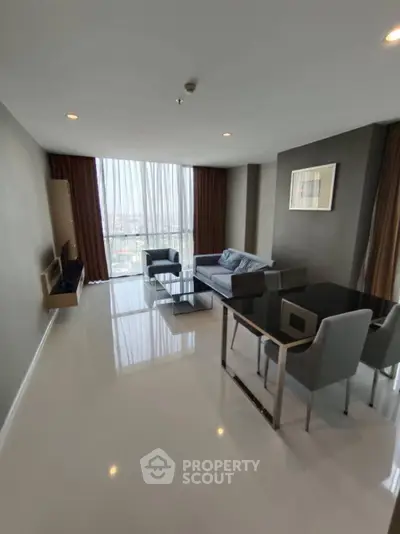 Modern living room with sleek furniture and large window offering city view.