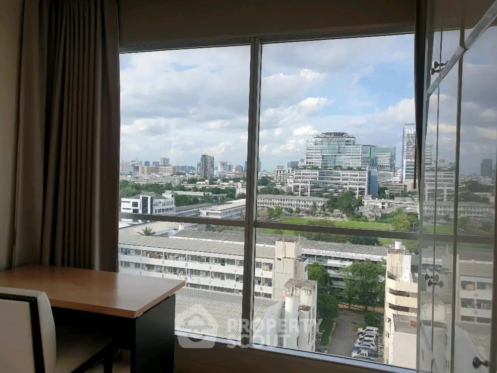 Stunning cityscape view from high-rise apartment window with desk and chair, perfect for work or relaxation.