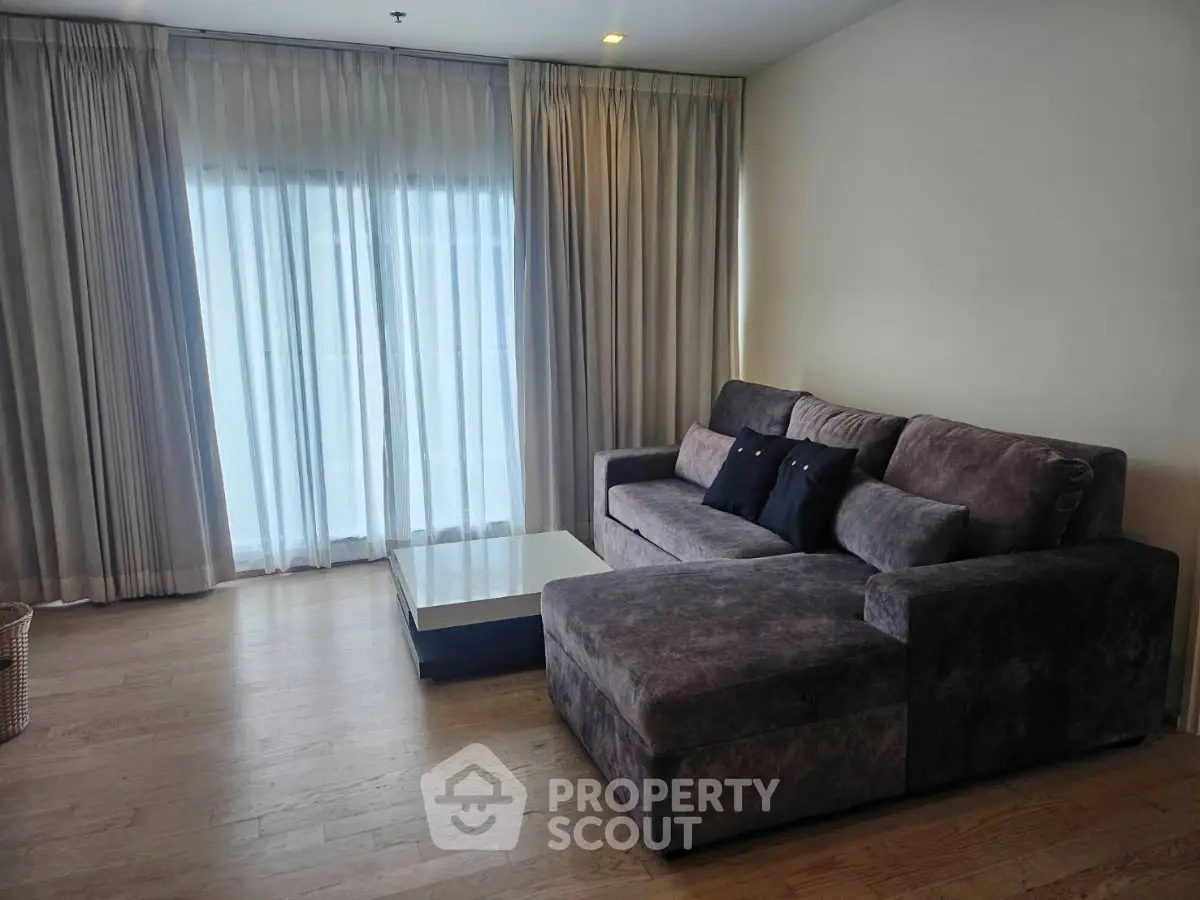 Spacious living room with plush sectional sofa and floor-to-ceiling curtains.