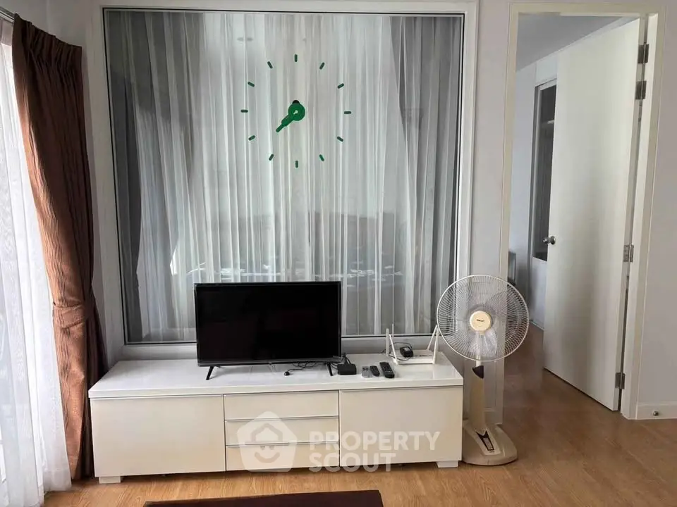 Modern living room with stylish decor, featuring a sleek TV stand, wall clock, and elegant curtains.