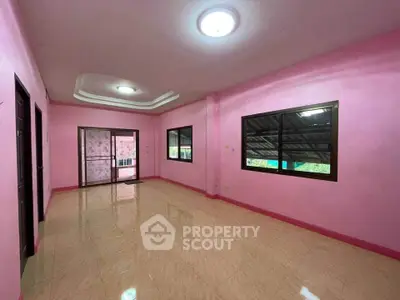 Spacious pink-walled room with large windows and glossy tile flooring, ideal for versatile use.