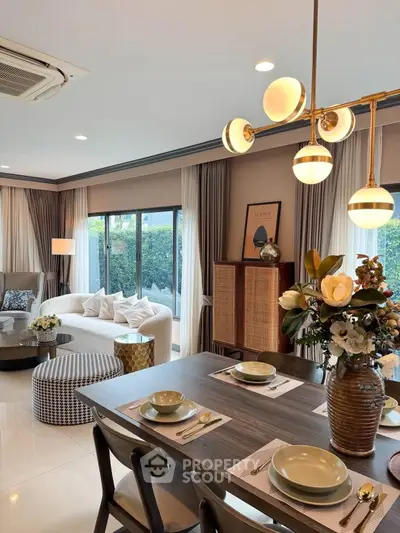 Luxurious living room with elegant decor and dining area, featuring modern lighting and garden view.