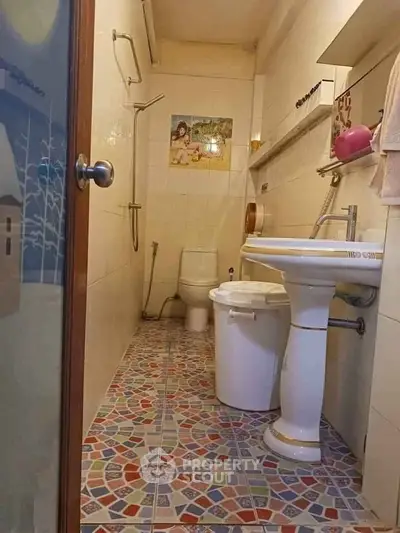 Charming bathroom with colorful mosaic floor tiles and classic pedestal sink.