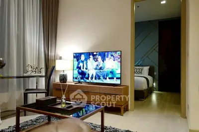 Modern living room with stylish decor and TV, adjacent to cozy bedroom.