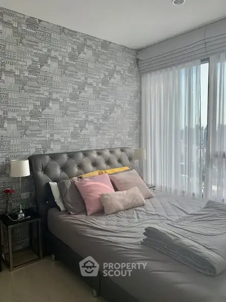 Cozy bedroom with stylish wallpaper and large window offering natural light.