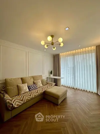 Spacious living room with elegant lighting and large window, featuring a cozy sofa and stylish decor.
