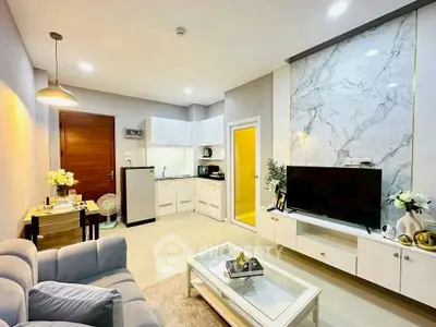 Modern living room with open kitchen, stylish decor, and marble accent wall.