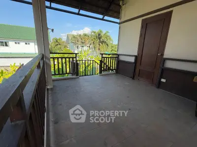 Spacious balcony with scenic view of lush greenery and neighboring houses, perfect for relaxation.