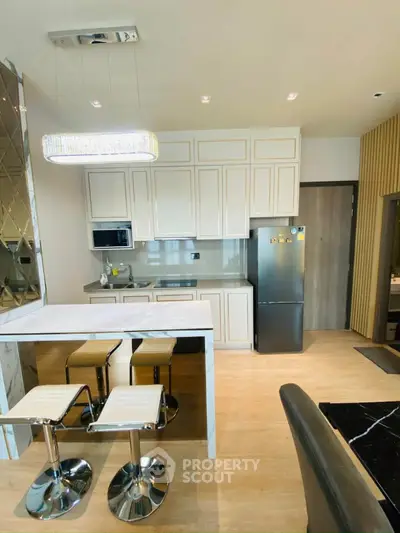 Modern kitchen with sleek design, marble countertop, and stylish bar stools in a contemporary apartment.
