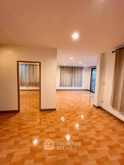 Spacious living room with wooden flooring and large windows for natural light.