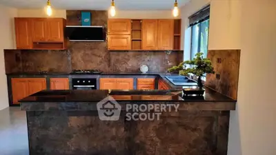 Modern kitchen with sleek countertops and wooden cabinets, featuring a gas stove and stylish lighting.
