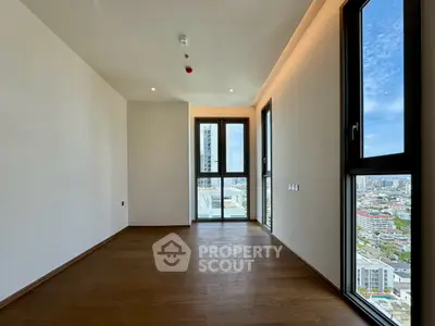 Spacious modern room with large windows offering stunning city views.